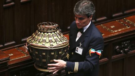 Un assistant parlementaire porte l'urne o&ugrave; sont gliss&eacute;s les bulletins des grands &eacute;lecteurs italiens, le 18 avril au Parlement, &agrave; Rome.&nbsp; (TONY GENTILE / REUTERS)