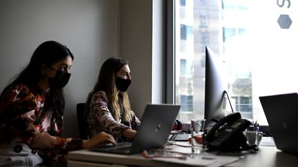 Des salariés portant un masque sanitaire dans un espace de co-working dans le quartier de La Défense, en octobre 2020. (CHRISTOPHE ARCHAMBAULT / AFP)