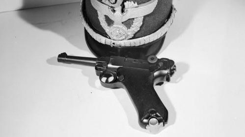 Un pistolet allemand Luger 9 mm accompagn&eacute; d'une casquette nazie, photographi&eacute;s en 1950. (ORLANDO / HULTON ARCHIVE / GETTY IMAGES)