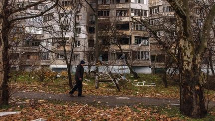 Un homme passe devant un bâtiment résidentiel à Kherson, dans le sud de l'Ukraine, le 25 novembre 2022. (ROMAN PILIPEY / EPA)