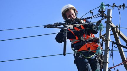 Un technicien Enedis répare un fil électrique, le 21 octobre 2021, à&nbsp;Plozévet (Finistère). (FRED TANNEAU / AFP)