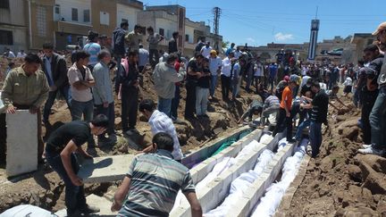 Une image transmise par une organisation de l'opposition montre des personnes enterrant des corps le 26 mai 2012, &agrave; Houla (Syrie). (SHAAM NEWS NETWORK / AFP)