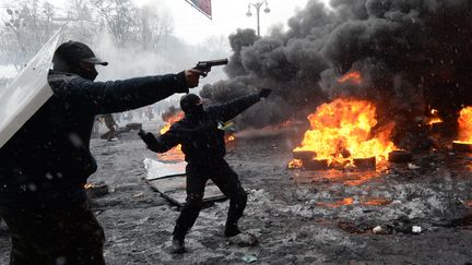 Des manifestants, armes au poing, tirent sur les forces de l'ordre ukrainiennes dans le centre de Kiev (Ukraine), le 22 janvier 2014.&nbsp; (VASILY MAXIMOV / AFP)