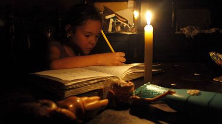 Une petite fille fait ses devoirs, éclairée à la bougie, à San Cristobal, au Venezuela, le 25 avril 2015.&nbsp; (CARLOS EDUARDO RAMIREZ / REUTEURS)