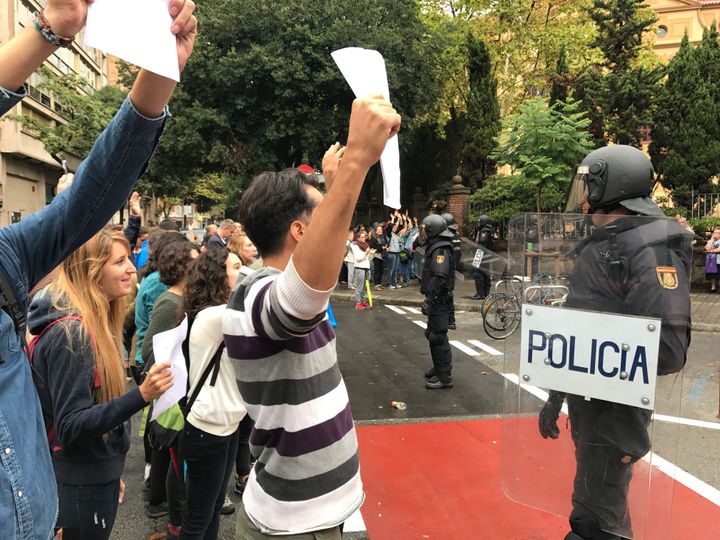 Des habitants brandissent des blletins de vote devant des policiers, à Barcelone, dimanche 1er octobre. (ROBIN / PRUDENT)