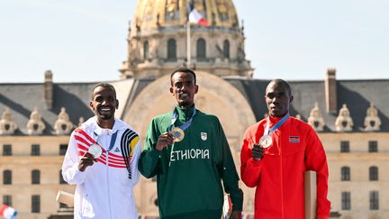 Le podium olympique du marathon avec le médaillé d'argent, à gauche, Bashir Abdi, le nouveau champion olympique au centre, Tamirat Tola, et à droite le médaillé de bronze Benson Kipruto, le 10 aôut 2024 aux Invalides. (ANDREJ ISAKOVIC / AFP)