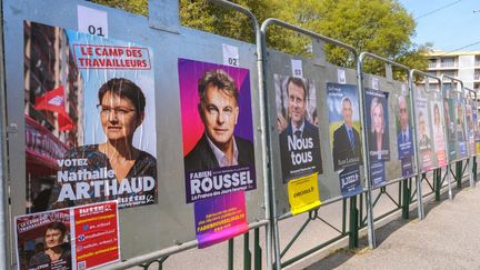 Des affiches de candidats à la présidentielle dont Nathalie Arthaud (LO), Fabien Roussel (PCF) et Emmanuel Macron à Valence (Drôme), le 28 mars 2022. (NICOLAS GUYONNET / HANS LUCAS / AFP)