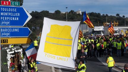 Les "gilets jaunes" "Tous unis",&nbsp; lors d'une manifestation au péage de l'autoroute A9 à Le Boulou dans les Pyrénées-Orientales, le 22 décembre 2018.&nbsp;
 (RAYMOND ROIG / AFP)