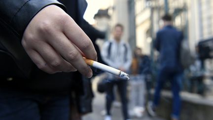 A person smokes a cigarette on the sidewalk in front of their school. Illustrative photo. (/NCY / MAXPPP)