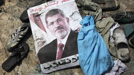 Une affiche de Mohamed Morsi, sur laquelle est &eacute;crit "Oui &agrave; la l&eacute;gitimit&eacute;, non au coup d'Etat", le 15 ao&ucirc;t 2013, au milieu des d&eacute;bris d'un camp de manifestants &eacute;vacu&eacute; la veille, au Caire (Egypte). (MOHAMED ABD EL GHANY / REUTERS)