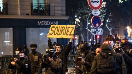 Paris, boulevard Saint-Germain, 17 novembre 2020. Un manifestant et sa pancarte derrière les photographes et journalistes qui protestent contre la proposition de loi relative à la sécurité globale dont certains articles visent à renforcer le contrôle des photos et vidéos de policiers sur les réseaux sociaux.&nbsp; (AMAURY CORNU / HANS LUCAS / AFP)