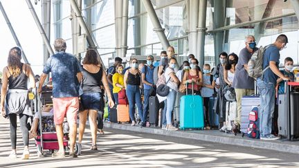 Des voyageurs patientent à l'extérieur de l'aéroport Felix-Eboue à Cayenne, en Guyane, le 10 juillet 2020. (JODY AMIET / AFP)