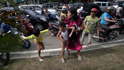 Une femme emm&egrave;ne ses enfants &agrave; l'int&eacute;rieur des terres dans la ville de Banda Aceh (Indon&eacute;sie) pour fuir un &eacute;ventuel tsunami, le 11 avril 2012. (CHAIDEER MAHYUDDIN / AFP)