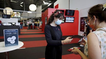 Une&nbsp;hôtesse vérifie le pass sanitaire d'une spectatrice dans un cinéma du&nbsp;groupe CGR à Carcassonne, le 21 juillet 2021. (BOYER CLAUDE / MAXPPP)