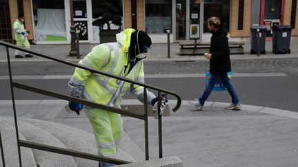 Un agent de propreté désinfecte le mobilier urbain à Suresnes (Hauts-de-Seine), le 18 mars 2020. (THOMAS SAMSON / AFP)