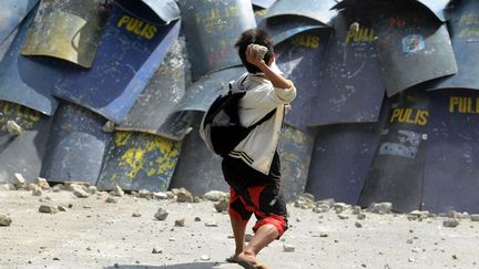 Un jeune gar&ccedil;on lance une pierre sur des policiers lors d'une op&eacute;ration de d&eacute;molition d'un bidonville &agrave; Manille (Philippines), le 27 janvier 2014. (NOEL CELIS / AFP)