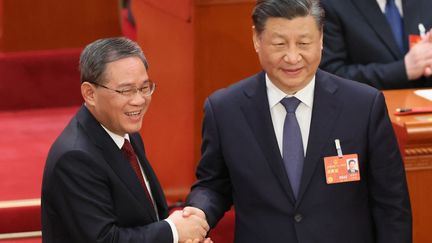 Li Qiang (à gauche) et Xi Jinping échangent une poignée de mains, le 11 mars 2023, à Pékin. (ICHIRO OHARA / YOMIURI / AFP)