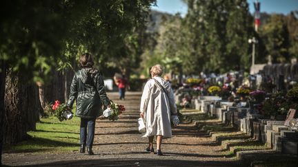 Deux femmes portent des fleurs dans un cimetière de Pau (Pyrénées-Atlantiques), le 29 octobre 2020. (QUENTIN TOP/HANS LUCAS/AFP)