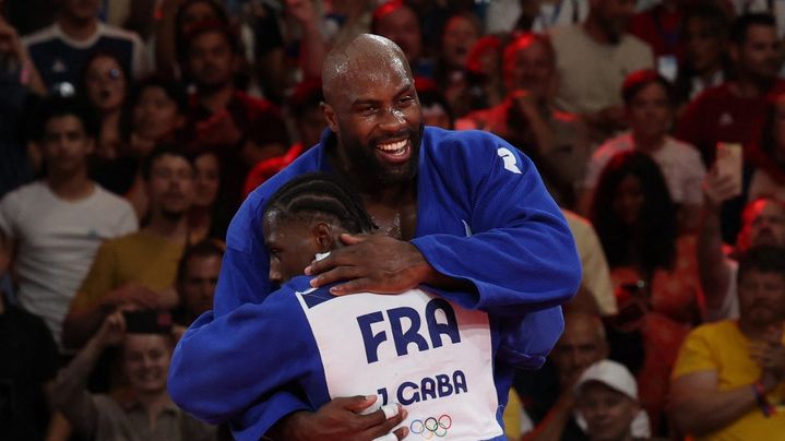 Teddy Riner félicité par Joan-Benjamin Gaba après avoir apporté le point décisif pour la France en finale de l'épreuve olympique par équipes mixte, le 3 août 2024. (JACK GUEZ / AFP)