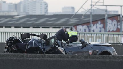 Des enqu&ecirc;teurs travaillent pr&egrave;s de la voiture de police d&eacute;truite dans la course-poursuite avec un 4x4, porte de la Chapelle, &agrave; Paris, le 21 f&eacute;vrier 2013. (KENZO TRIBOUILLARD / AFP)