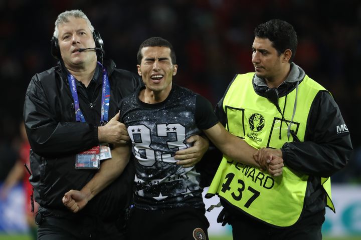 Des stadiers emmènent un jeune fan ému de Cristiano Ronaldo, après son intrusion sur la pelouse du Parc des Princes, samedi 18 juin 2016. (KENZO TRIBOUILLARD / AFP)