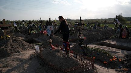 Une femme ukrainienne visite la tombe de son mari retrouvé dans une fosse commune, à Boutcha, le 12 mai 2022. (HIROTO SEKIGUCHI / YOMIURI / AFP)