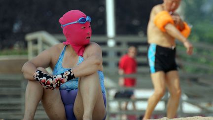 Une Chinoise porte un "face-kini" et des gants afin de se prot&eacute;ger du soleil, des piq&ucirc;res d'insectes et des m&eacute;duses sur une plage de Qingdao (Chine), le 3 juillet 2013. (AFP)