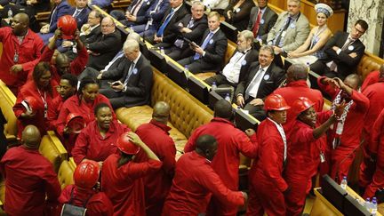 Les députés de l'opposition radicale vêtus de leurs combinaisons rouges quittent l'hémicyle du parlement sud-africain dans le vacarme, le 11 février 2016. Ils ont interrompu pendant une heure le discours de Jacob Zuma. (Photo AFP/Schalk Van)