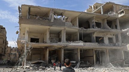 Un enfant face à un immeuble en ruines, dans la Ghouta orientale, fief rebelle aux portes de Damas, la capitale syrienne, le 1er mars 2018. (AMER ALMOHIBANY / AFP)