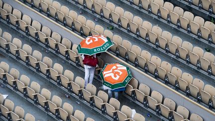 Des spectateurs&nbsp;s'abritent de la pluie,&nbsp;le 4 juin 2019 à Roland-Garros. (MARTIN BUREAU / AFP)