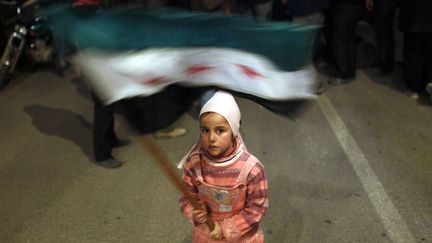 Une petite fille agite le drapeau de l'opposition syrienne lors d'une manifestation contre le pr&eacute;sident Bachar el-Assad &agrave; Al Qusayr (Syrie), le 27 f&eacute;vrier 2012. (GORAN TOMASEVIC / REUTERS)