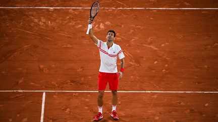 Novak Djokovic lève sa raquette au ciel après sa victoire en demi-finale de Roland-Garros 2021 contre Rafael Nadal au terme d'un match d'exception le 11 juin 2021 (CHRISTOPHE ARCHAMBAULT / AFP)