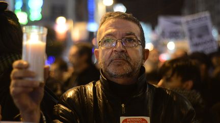 Un homme tient une chandelle pour protester contre le budget d'aust&eacute;rit&eacute; adopt&eacute; pour 2013, &agrave; Madrid (Espagne), le 20 d&eacute;cembre 2013. (PIERRE-PHILIPPE MARCOU / AFP)