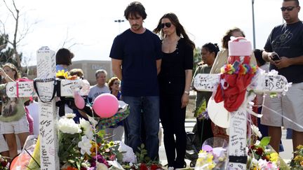 L'acteur Christian Bale et sa femme Sandra Blažić&nbsp;se recueillent devant le m&eacute;morial dress&eacute; en hommage aux 12 personnes tu&eacute;es lors d'une fusillade dans un cin&eacute;ma d'Aurora (Colorado), le 24 juillet 2012. (JOSHUA LOTT / GETTY IMAGES)