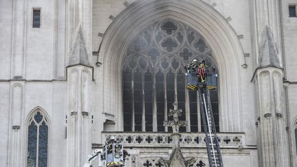 Des policiers tentent d'éteindre l'incendie qui ravage la cathédrale&nbsp;Saint-Pierre-et-Saint-Paul de Nantes (Loire-Atlantique), le 18 juillet 2020. (SEBASTIEN SALOM-GOMIS / AFP)