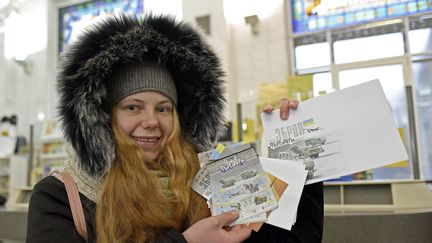 Une Ukrainienne montre une série de timbres achetés dans un bureau de poste de Kiev (Ukraine), le 6 décembre 2022. (RUSLAN KANIUKA / NURPHOTO / AFP)