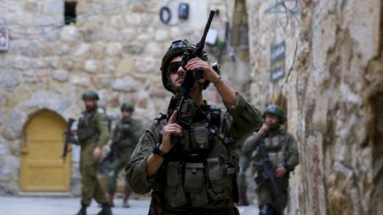 Un soldat israélien pointe son arme dans la vieille ville d'Hébron, en Cisjordanie, le 4 janvier 2025. (MOSAB SHAWER / IMAGES MOYEN-ORIENT / AFP)