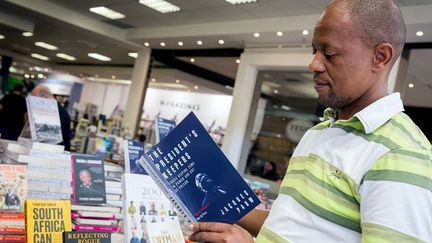 Un Sud-Africain découvre le livre du journaliste Jacques Pauw dans une librairie de Durban le jour de sa parution, le 29 octobre 2017. (Photo AFP/Rajesh Jantilal)