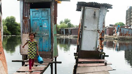 Eriam Sheikh, âgée de 7 ans, vient de sortir d’une cabine de toilettes sur pilotis, dans le quartier Rafiq Nagar, à Mumbai, en Inde. (UNICEF / MANPREET ROMANA)