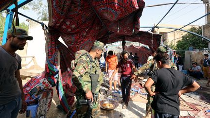 Des Irakiens, dont des membres des forces de sécurité, sur les lieux d'un attentats qui a visé la communauté chiite, à Bagdad, samedi 15 octobre 2016.&nbsp; (SABAH ARAR / AFP)