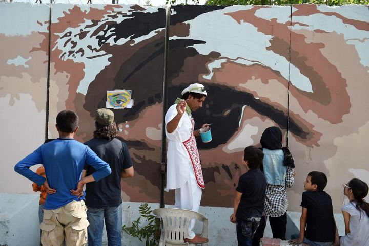 Kabir, artiste afghan, peint des yeux géants sur un mur de Kaboul pour dénoncer la corruption, avec l'aide de volontaires. 
 (WAKIL KOHSAR / AFP)