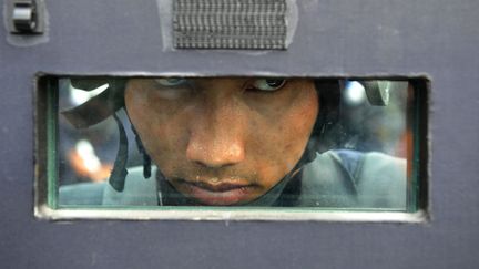 Un policier observe les manifestants &agrave; travers son &eacute;quipement &agrave; Bangkok (Tha&iuml;lande), le 14 f&eacute;vrier 2014. (MANJUNATH KIRAN / AFP)