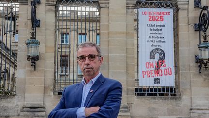 Le maire de Bordeaux, devant l'une des banderolles affichées sur le fronton de l'hôtel de ville. (GUILLAUME BONNAUD / MAXPPP)