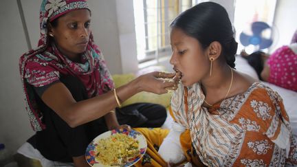 Une adolescente de 16 ans, amput&eacute;e d'une main apr&egrave;s 36 heures sous les d&eacute;combres, est nourrie par sa m&egrave;re dans un h&ocirc;pital de Savar, le 4 mai. (ANDREW BIRAJ / REUTERS)