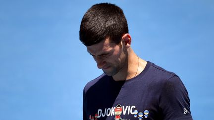 Novak Djokovic, la tête baissée, ici à l'entraînement sur un court du Melbourne Park, mercredi 12 janvier 2022. (WILLIAM WEST / AFP)