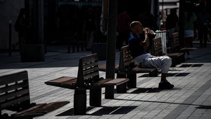 Une personne assises sur un banc boit de l'eau, à Lyon, le 23 août 2023. (NICOLAS LIPONNE / HANS LUCAS / AFP)