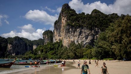 Des touristes marchent le long d’une plage à Railay,en Thaïlande. (JACK TAYLOR / AFP)