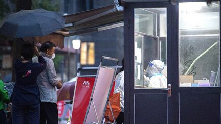 Un agent de santé se prépare à faire un test pour le Covid-19 covid&nbsp;sur un résident de la ville de&nbsp;Xian, dans la province chinoise du Shaanxi (nord). (STR / AFP)