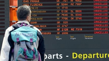 A Roissy, un passager regarde le tableau des vols "annulés". (AFP - THOMAS COEX)