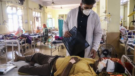 Un médecin aide un patient atteint du Covid-19 à l'hôpital NSSCB de Jabalpur, le 20 mai 2021. (UMA SHANKAR MISHRA / AFP)